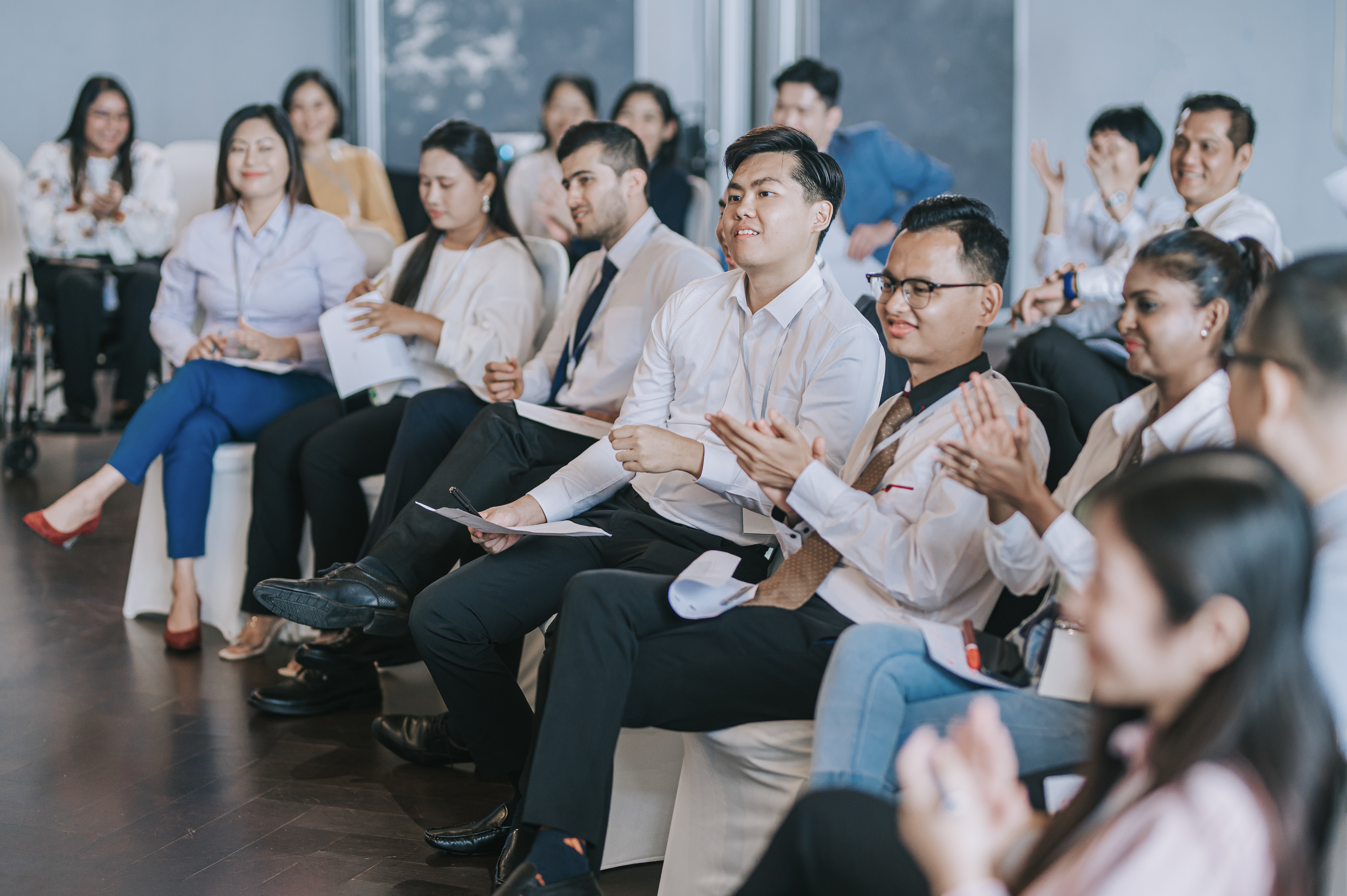 Asian seminar participants applauding listening to presenter on stage